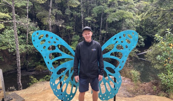 A GW staff member posing with the butterfly wings installed at Butterfly Creek