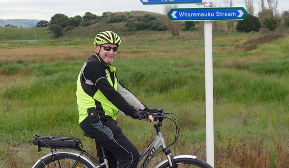 A man on a bike smiles at the camera