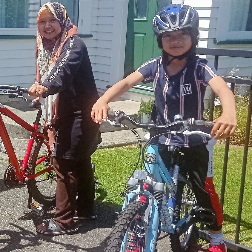 A woman and child with bikes smile at the camera