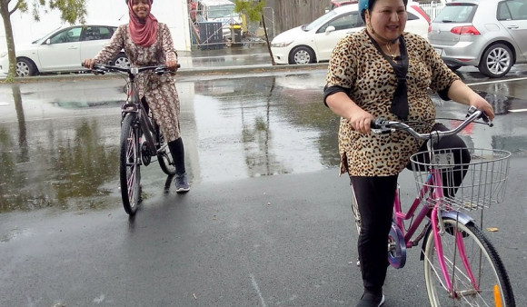 Two women on bikes smile at the camera