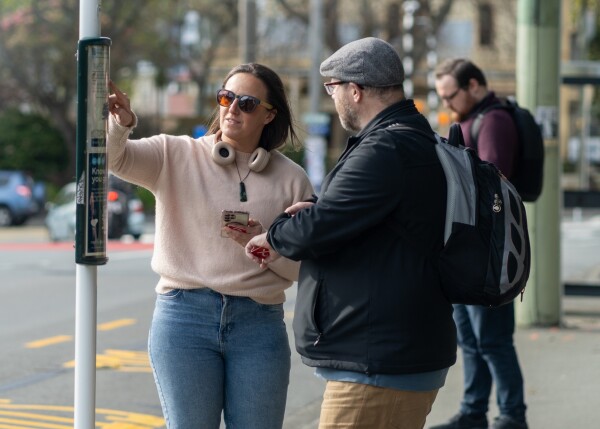 Two people looking at the paper timetable at a bus stop