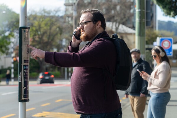 A person on a phone call looking at the paper timetable at a bus stop