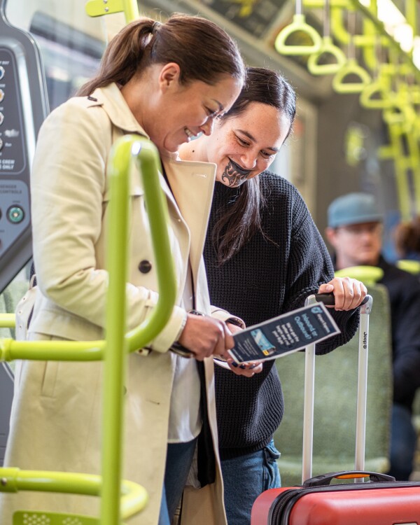 Two women on a train looking at a paper timetable