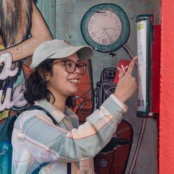 A person looking at the paper timetable at a bus stop and holding their Snapper card