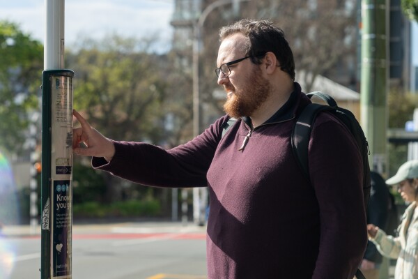 A person looking at the paper timetable at a bus stop