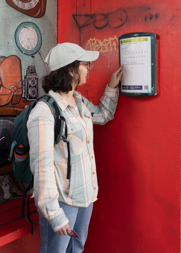A person looking at the paper timetable at a bus stop
