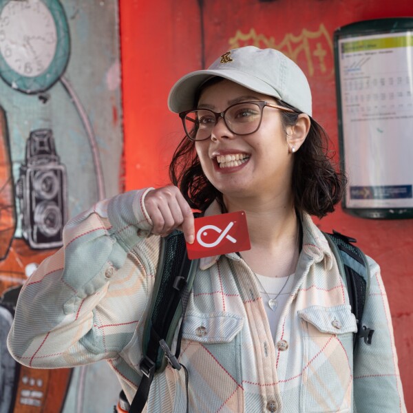 A person at a bus stop holding their Snapper card