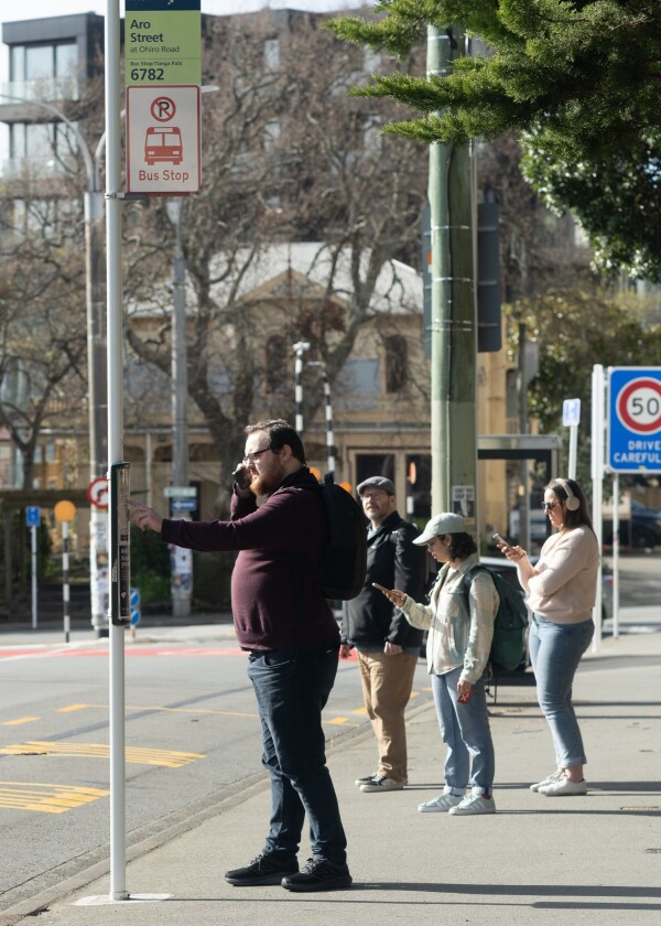 A group of people wait at a bus stop