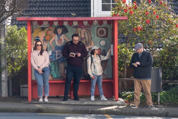A group of people wait at a bus stop