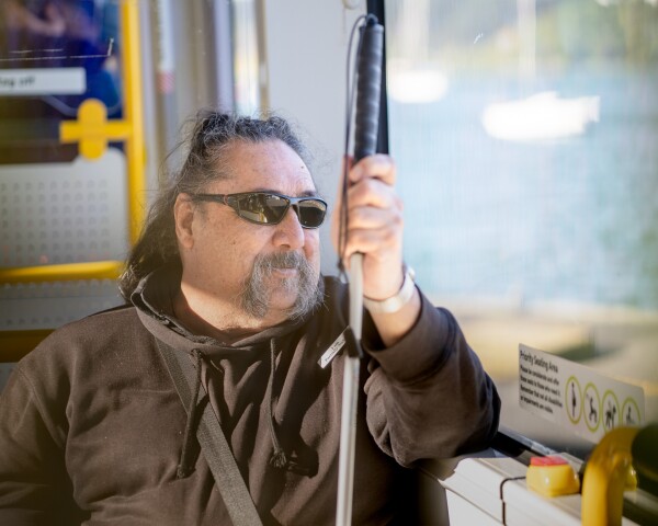 A person with a cane sitting on a bus