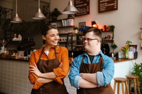 Two baristas smile at each other in a cafe