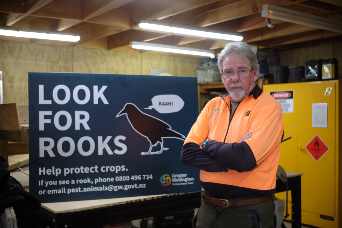 Steve Playle standing in front of a Greater Wellington ‘Look for Rooks’ sign
